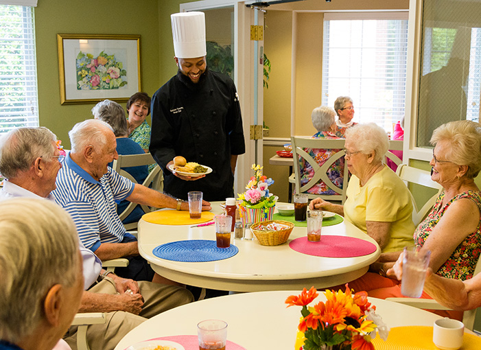 residents in dining room talking to chef